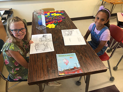 2 students seated at table with books