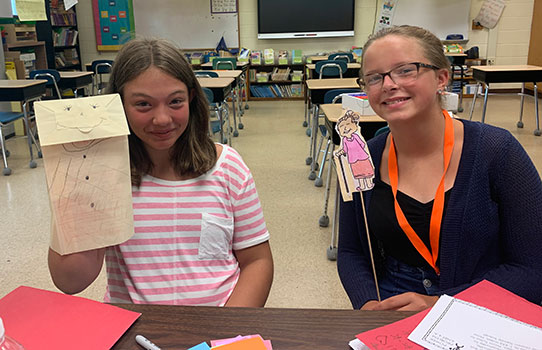 2 students holding puppets they made