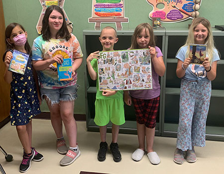group of students holding a book and a completed puzzle