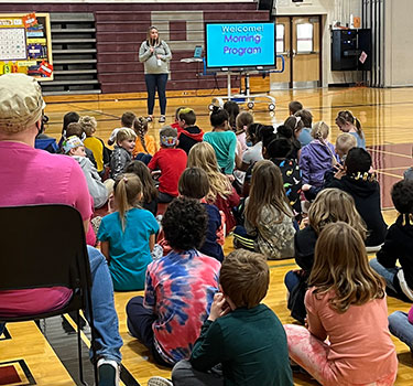 Ashley Bargstedt introduces Sergeant Smith and K9 Bud to students in gym