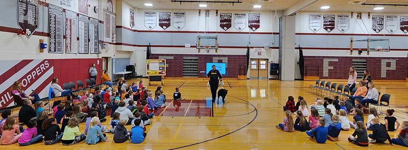 students and staff in gym with Sergeant Smith and K9 Bud