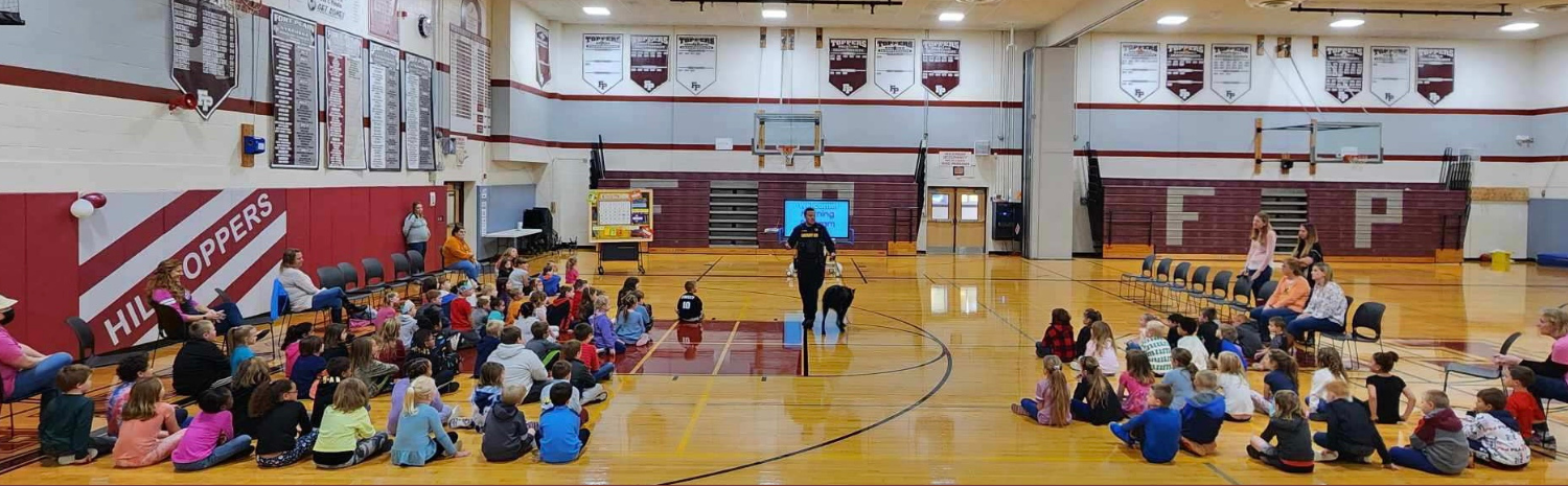 Sergeant Smith and K9 Bud with students and staff in gym