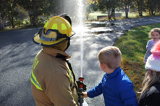 firefighter and student holding fire hose