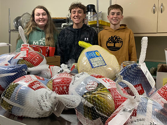Andra Fuhs, Stephen Gray and Mason Gray with donated turkeys and food