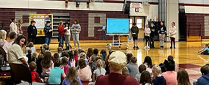 Adult and students at veterans assembly in the gym