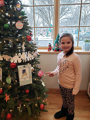 student pointing to ornament hanging on tree