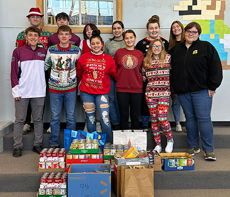 group of students standing behind boxes of food