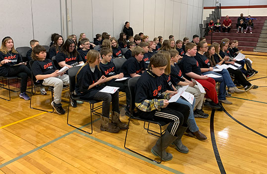 students seated in a group looking at their DARE diplomas