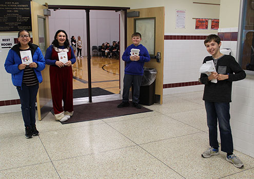 3 students holding programs outside the gym