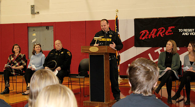 Deputy talking at the podium while other adults and students listen
