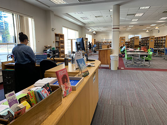 view of the librarian's desk with students working beyond at tables