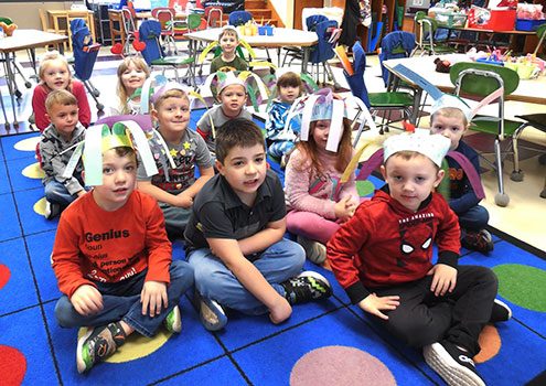 group of seated students wearing paper hats they created