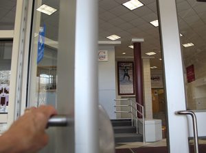 hand opening exterior door with banner in view beyond