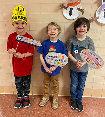 3 students holding 100th day of school signs