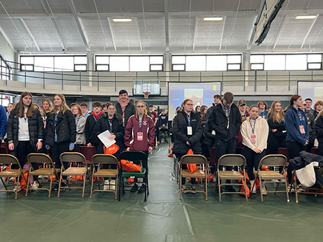 students standing in front of their chairs at the conference