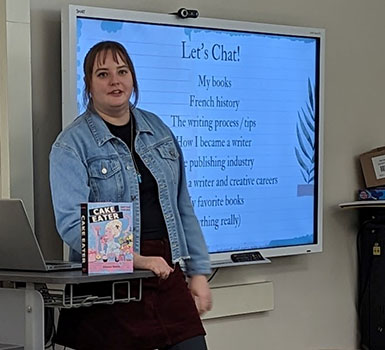 Allyson standing in front of a video screen with her book in front of her