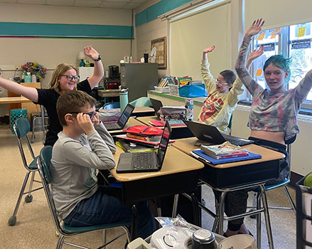 students with their hands raised in the air and seated student