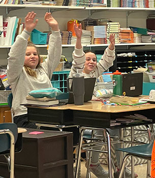 students with their hands raised in the air