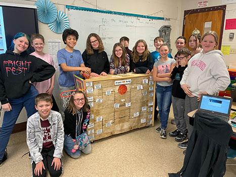 group of students standing around tournament bracket board