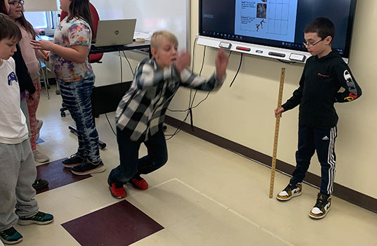 student jumping forward while other students watch