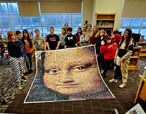 students holding big pixelated image of "Mona Lisa"