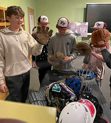 students look at baseball gloves and hats