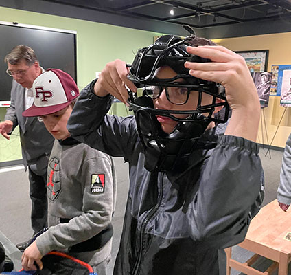 student holding a catcher's mask on his head