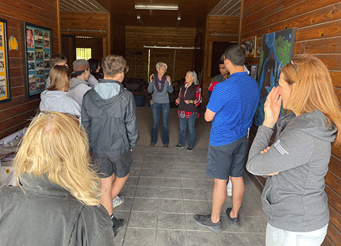 students inside a horse barn listening to an adult