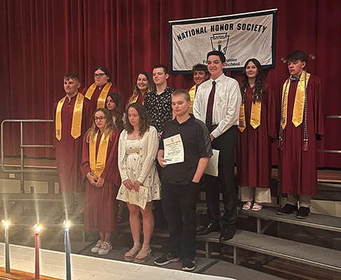 NHS member students stand in a group on stage