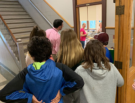 students and adults outside classroom door, with teachers inside looking out at them