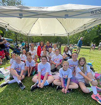 group of students seated under a sun shelter outside