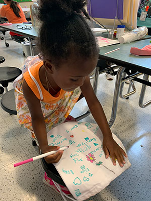 student decorating a string bag with a fabric marker