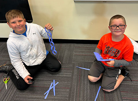 students holding a paper chain and piece of paper