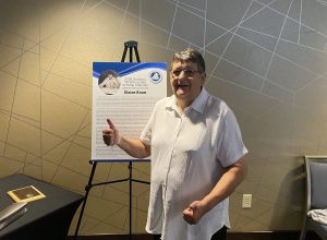 Former Fort Plain wrestling coach Elaine Krum gives a thumbs up and smiles for the camera near the awards table at the Upstate New York Chapter of the Wrestling Hall of Fame induction.